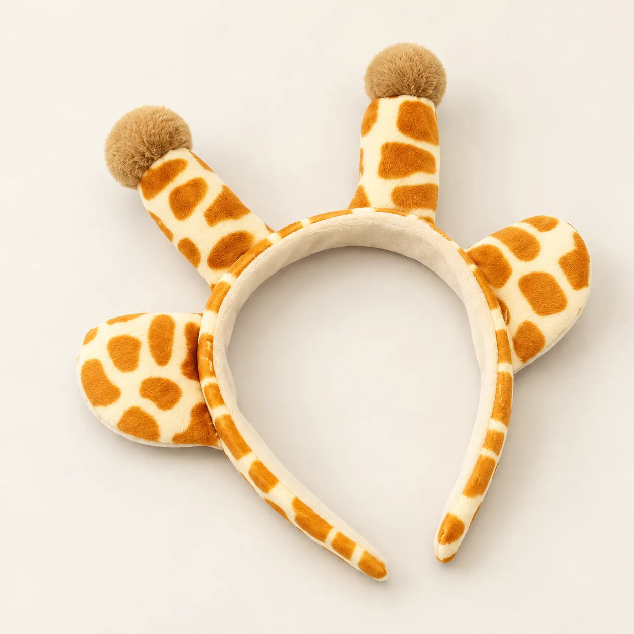 Plush giraffe ear headband with spotted ears and two small horns with brown pom-pom tips