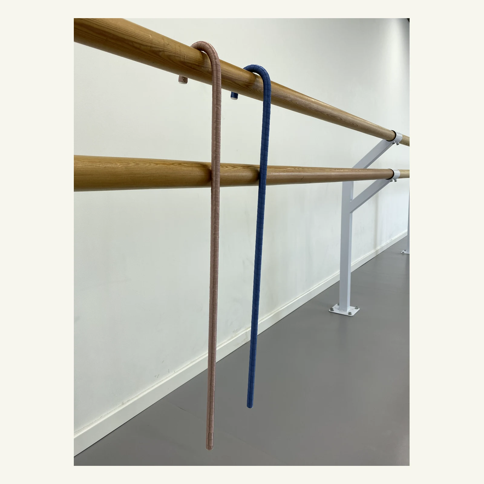 Blue and pink ballet canes hanging from the barre by their hooks