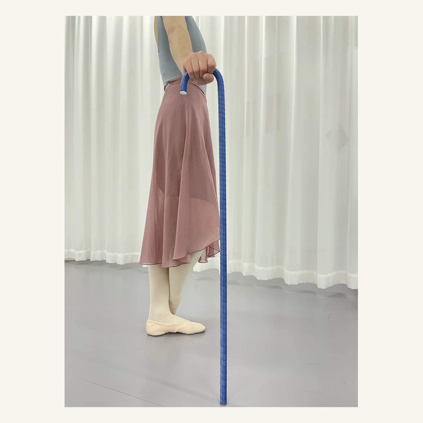 Dancer resting a hand on the hook of the blue ballet cane
