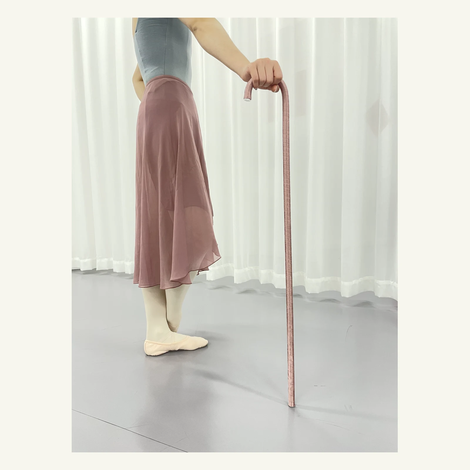 Dancer resting a hand on the hook of the pink ballet cane