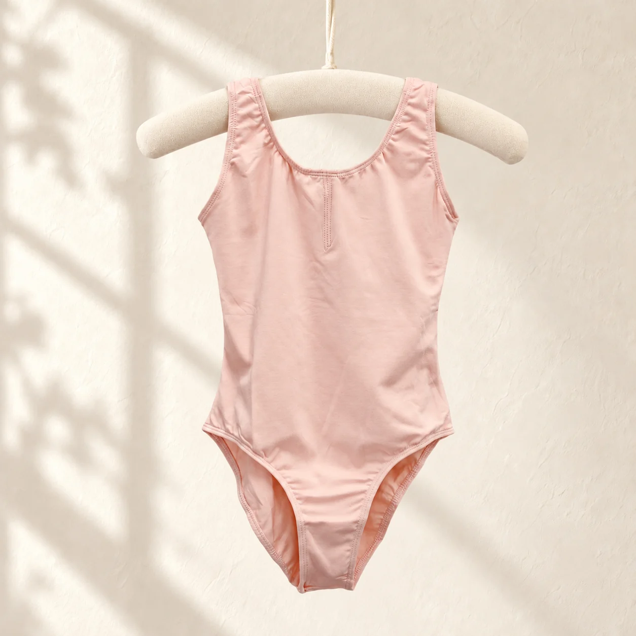 Light pink sleeveless cotton ballet leotard on a hanger
