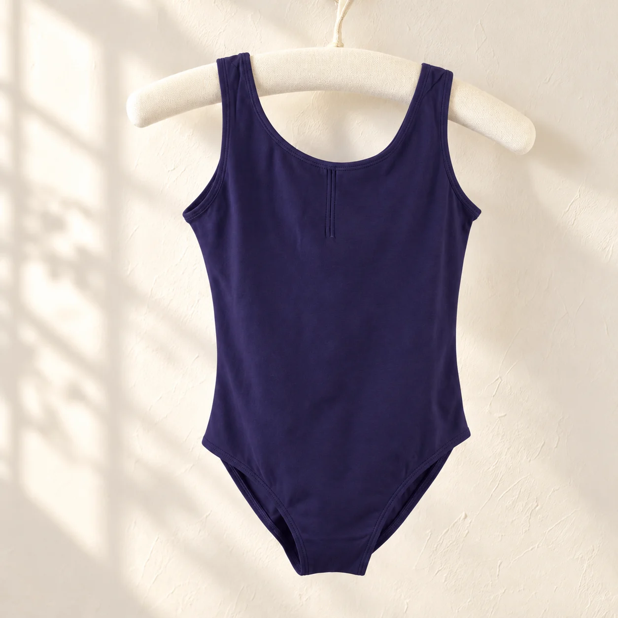 Dark purple sleeveless nylon ballet leotard on a hanger