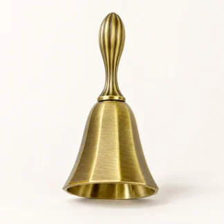 Antique brass hand bell with a grooved handle on a white background