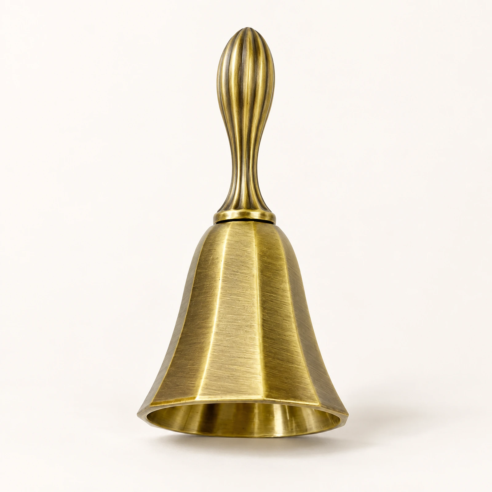 Antique brass hand bell with a grooved handle on a white background