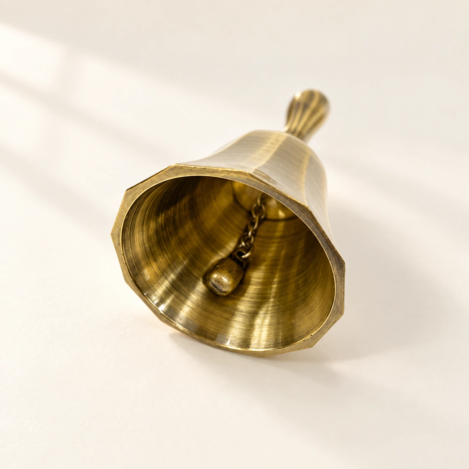 Inside of the brass hand bell showing the clapper on a short chain