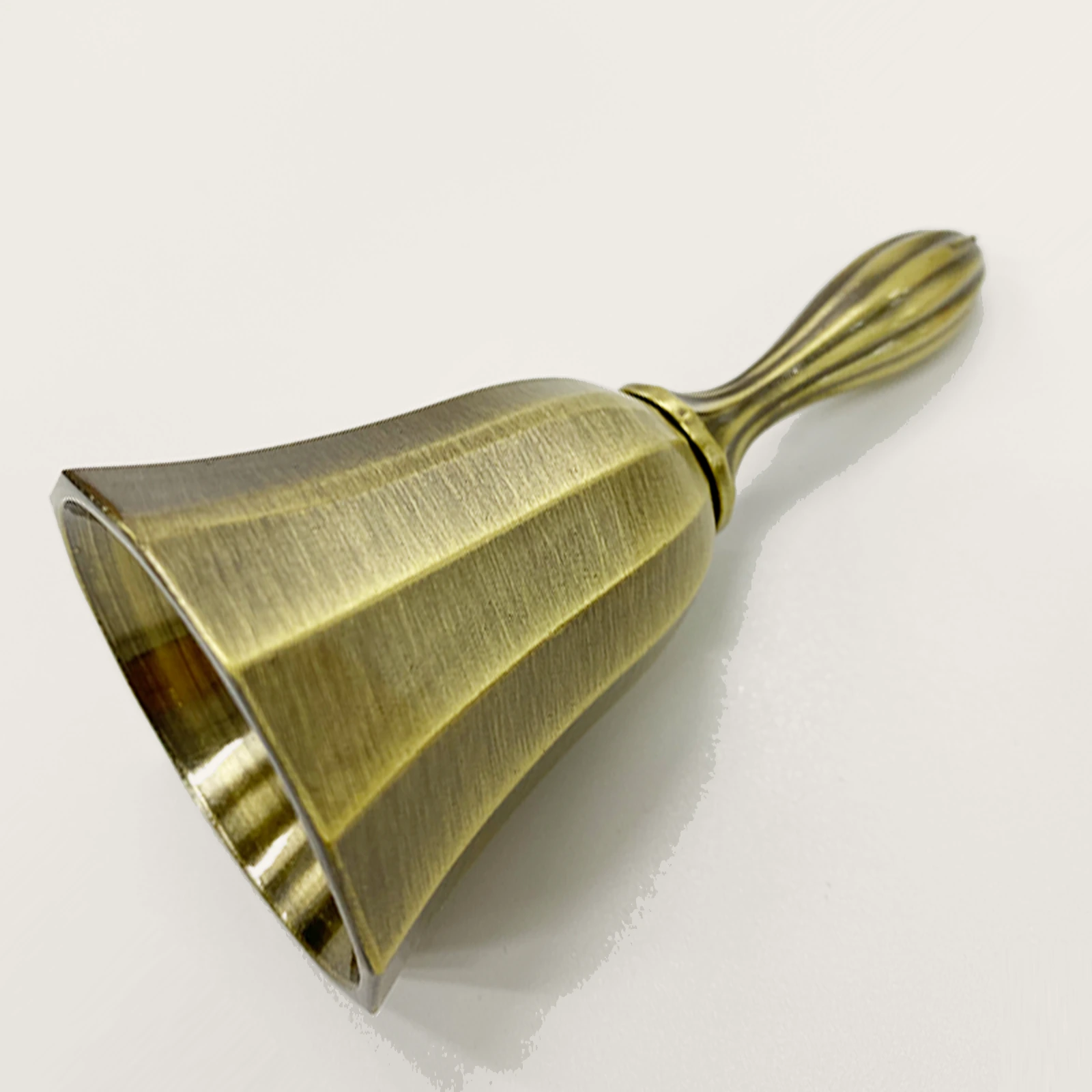 Antique brass hand bell lying on its side showing the finish
