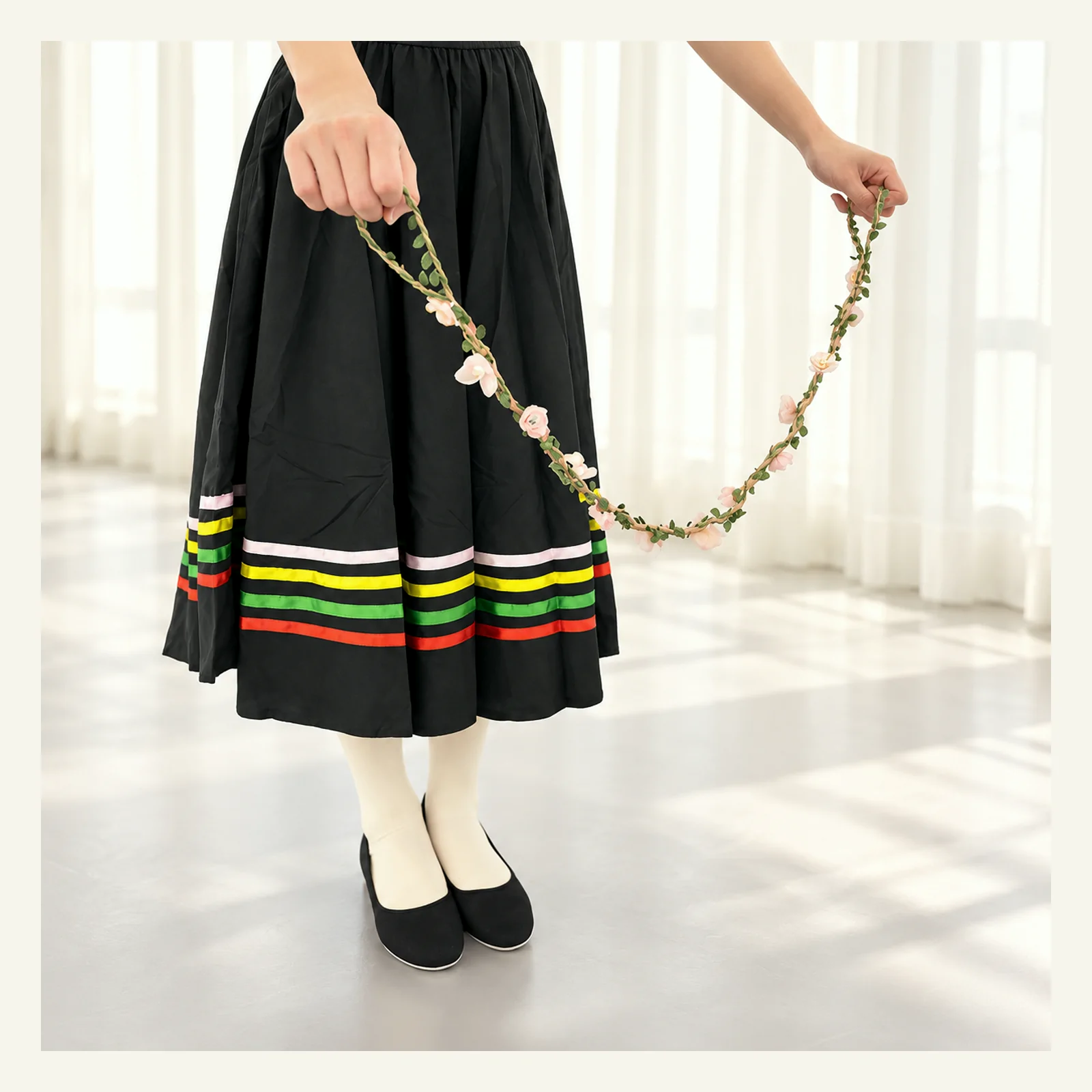 Dancer in a black character skirt holding the flower wreath in both hands