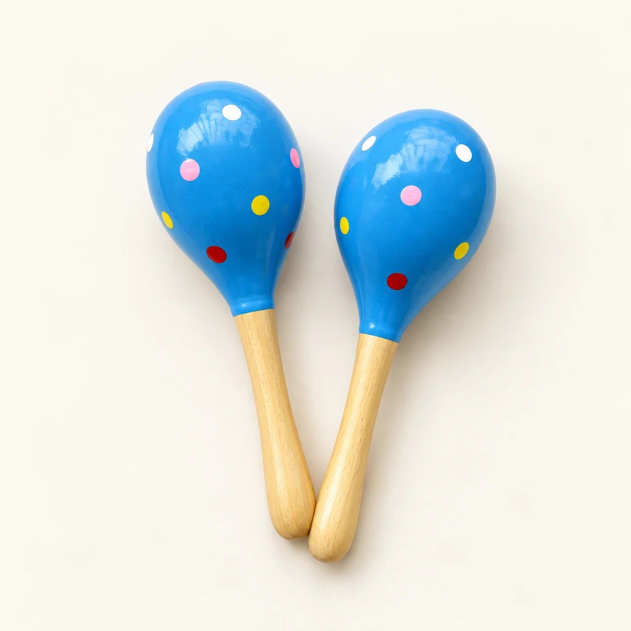 A pair of blue painted wooden hand shakers with colorful dots and natural wood handles