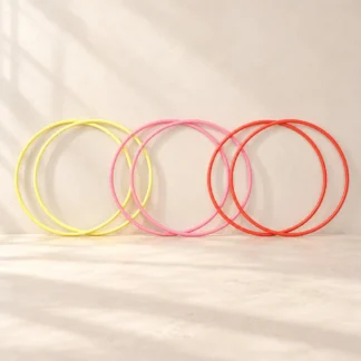Six jump hoops in yellow, pink and red standing in pairs against a cream wall
