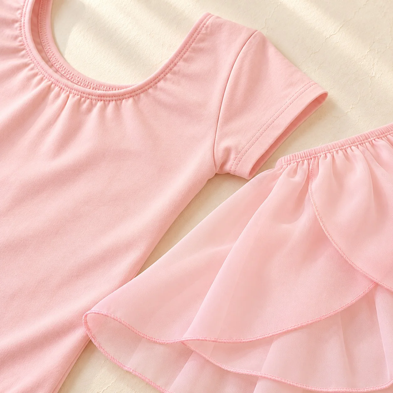 Close-up of the pale pink leotard neckline and sleeve with the layered chiffon skirt