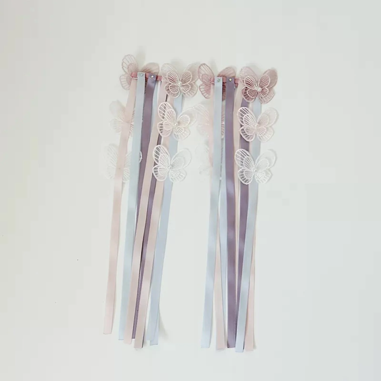 Pair of butterfly wrist ribbons hanging against a plain wall